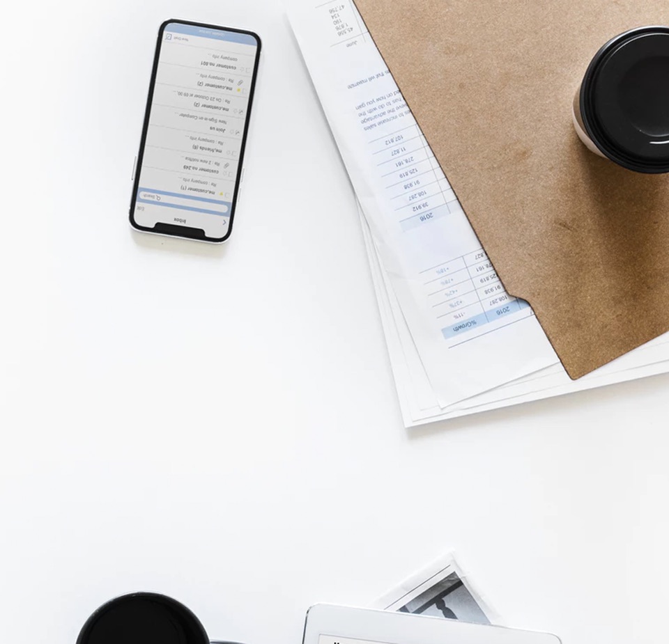View of an iphone and a coffee cup on top of a folder full of papers